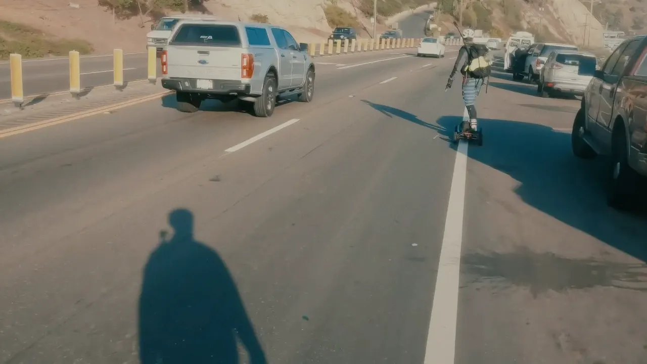 Traffic on the Pacific Coast Highway, a rider’s shadow on the road.