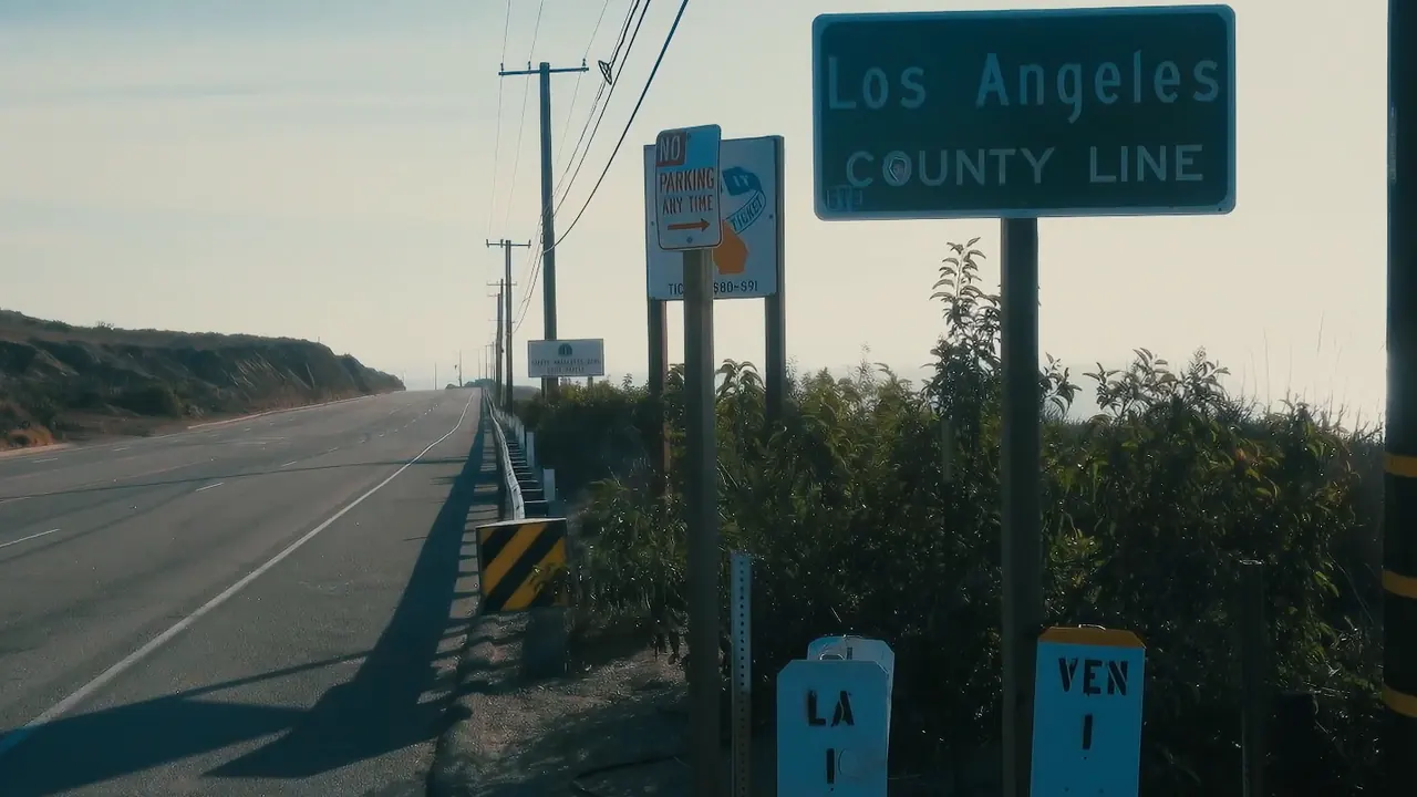 The green Los Angeles County Line sign beside the coast highway.