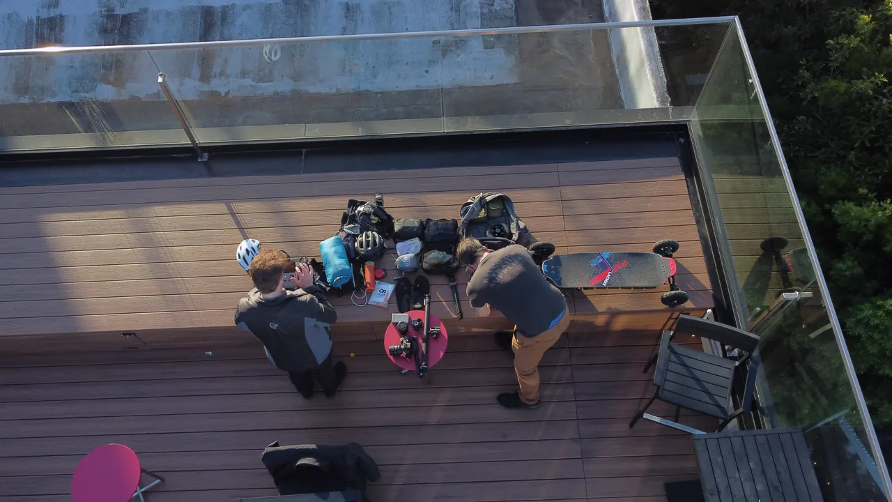 From a drone: the two riders on a rooftop deck in San Francisco, their gear spread out around them.