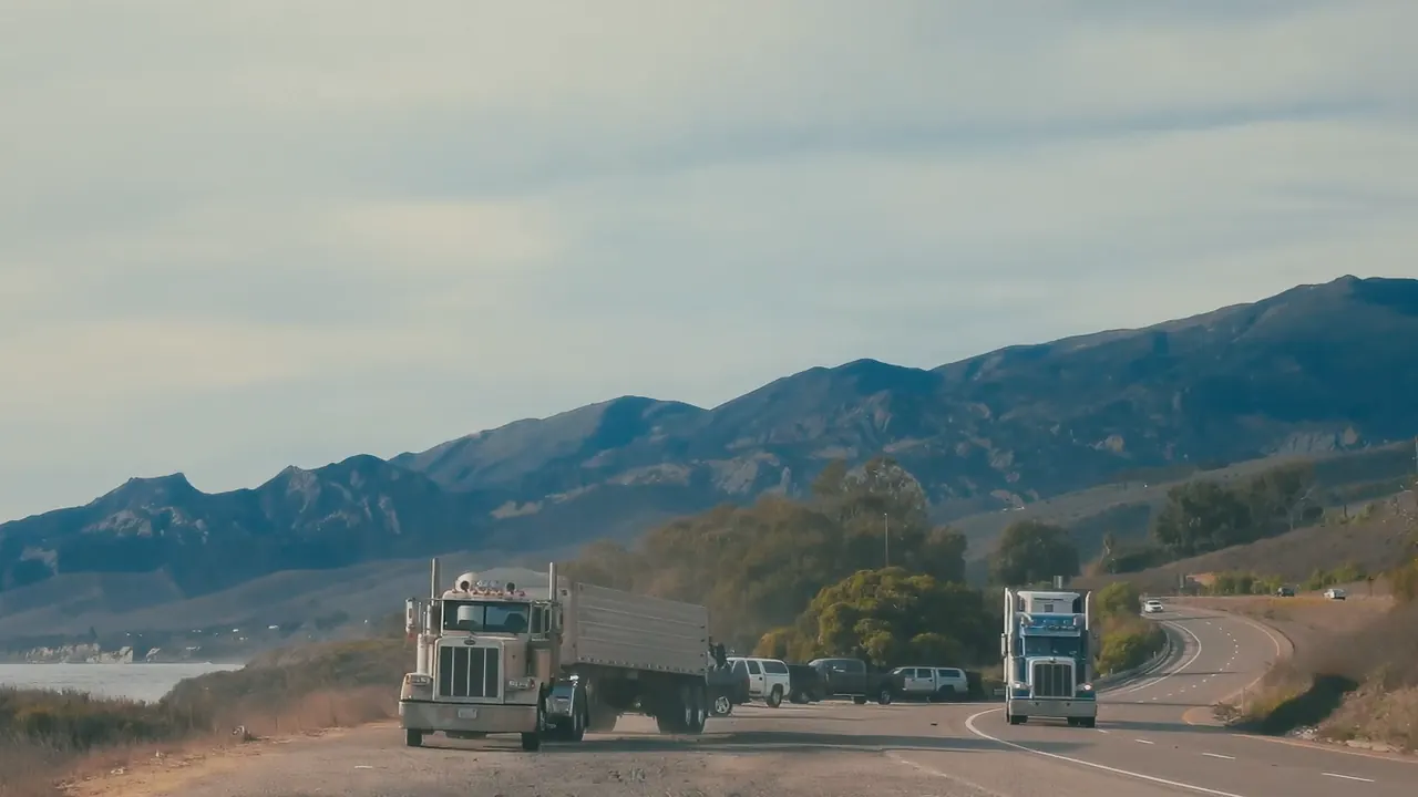 A big rig thundering past a rider on the freeway shoulder.