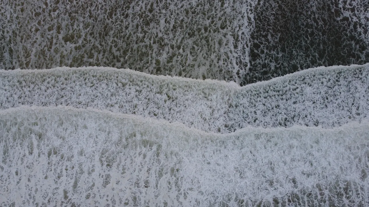From a drone at dawn: white water breaking on the beach at Pismo.