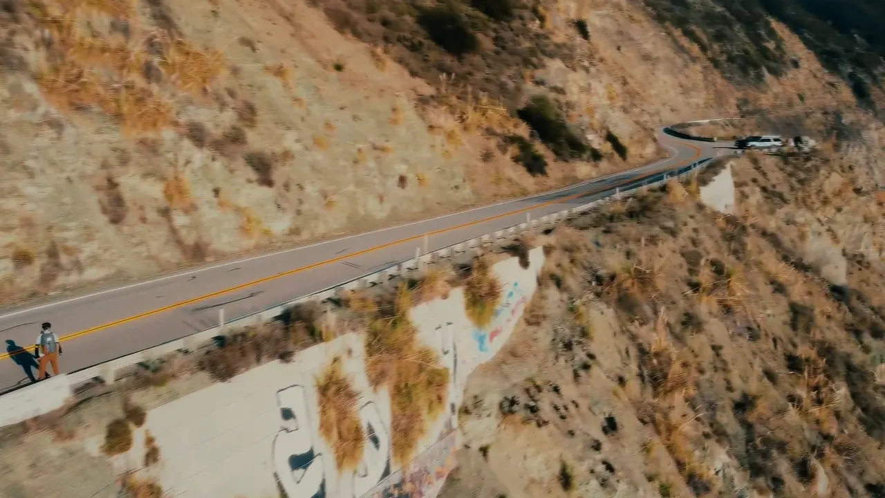 From a drone: a rider on the empty cliffside highway in Big Sur, far above the sea.