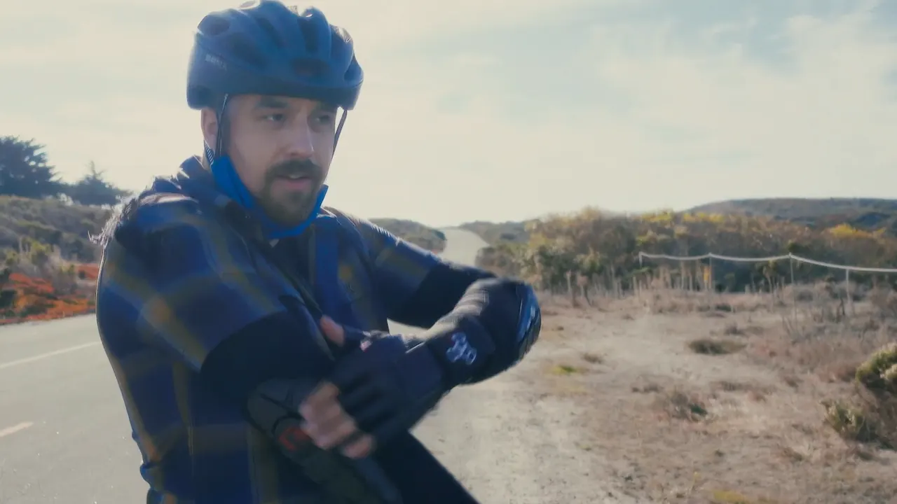 A rider in a plaid shirt and helmet showing the camera his elbow after the fall.
